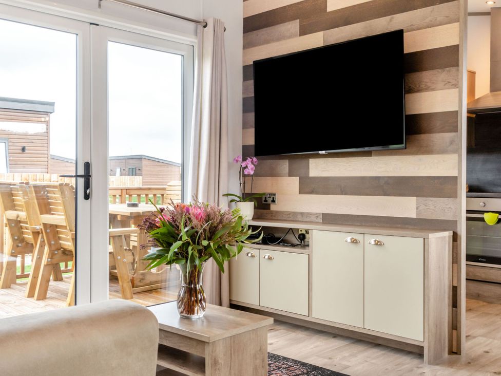 A living room with a television and a flower vase at Kinder Spa in Carlton Miniott near Thirsk