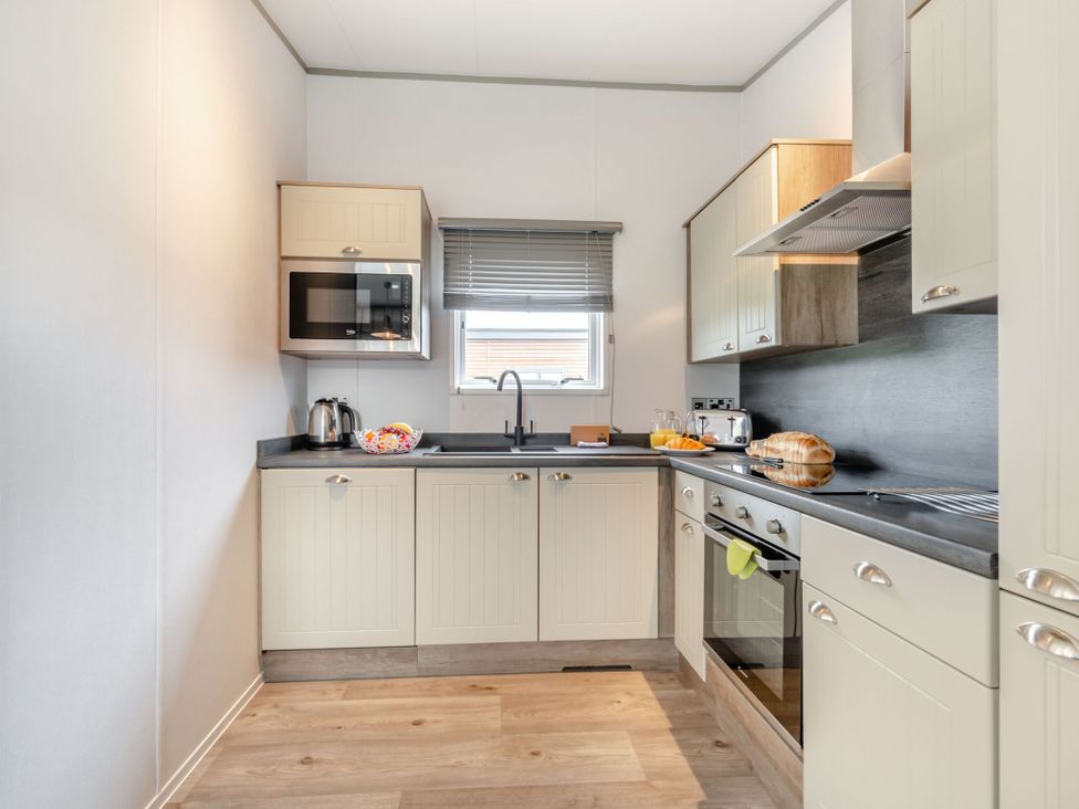 A kitchen with appliances and a window at Kinder Spa (Pet) Carlton Miniott near Thirsk