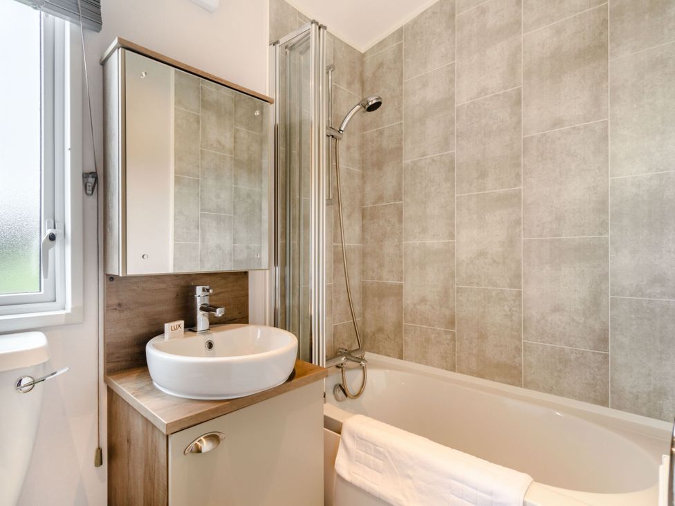 A bathroom with a bathtub, sink, and shower at Kinder Spa (Pet) Carlton Miniott near Thirsk