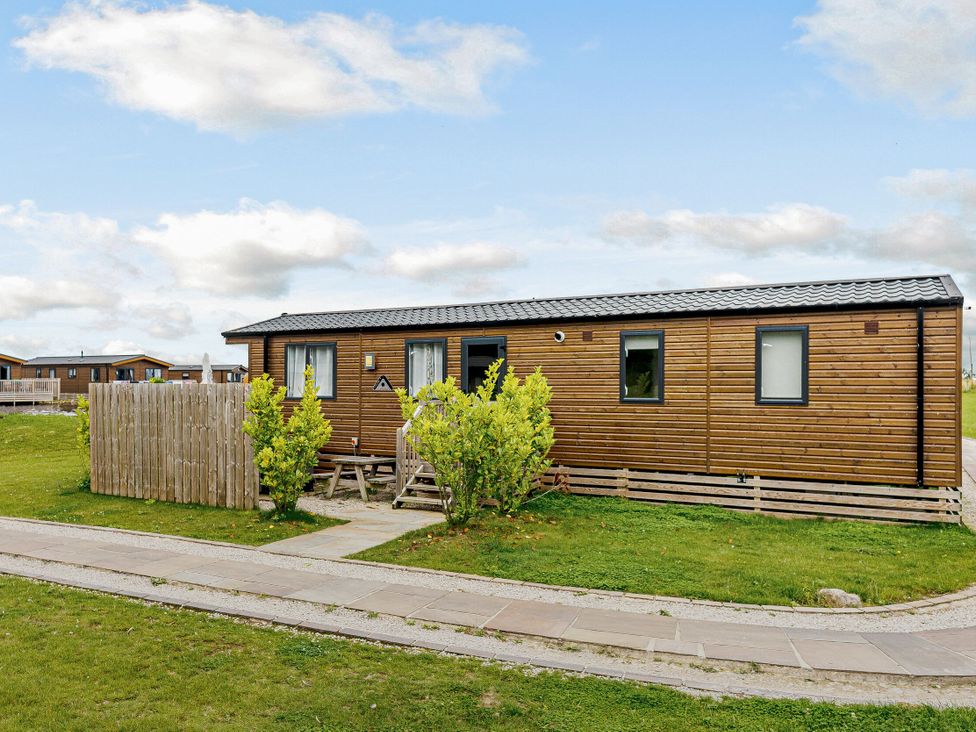 A building with a wooden exterior and garden area at Alder Waterside Spa (Pet) Carlton Miniott near Thirsk