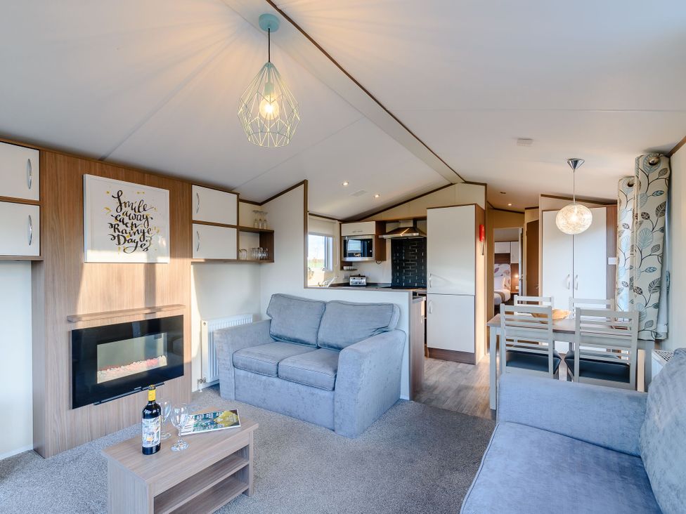 A living room with a sofa and dining area at Alder Waterside Spa (Pet) Carlton Miniott near Thirsk