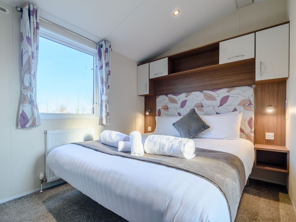 A bedroom with a bed and window at Alder Waterside Spa (Pet) Carlton Miniott near Thirsk