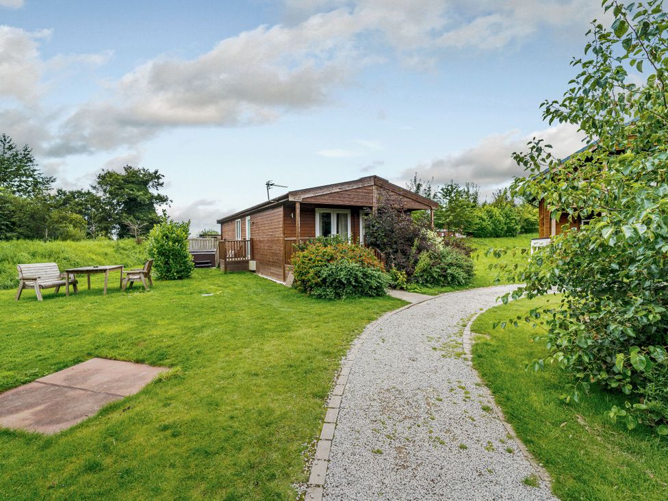 A cabin with a pathway and seating area at Fir Tree Waterside Spa Carlton Miniott near Thirsk