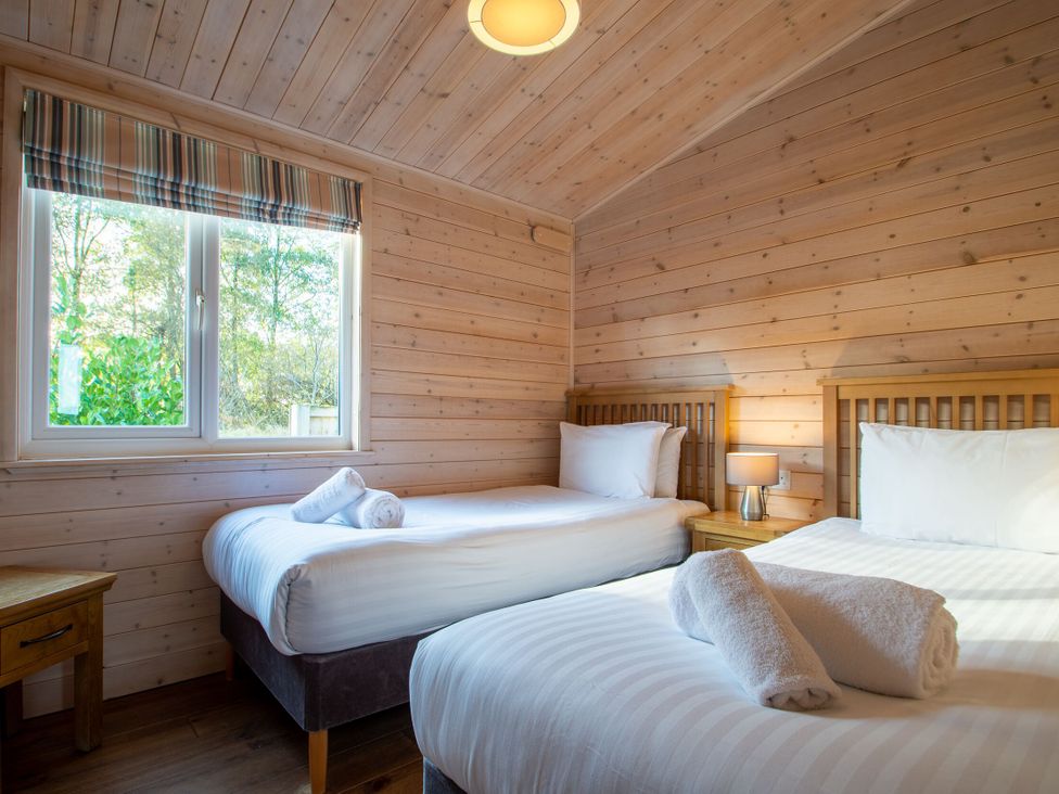 A bedroom with two single beds and a window at Fir Tree Waterside Spa in Carlton Miniott near Thirsk