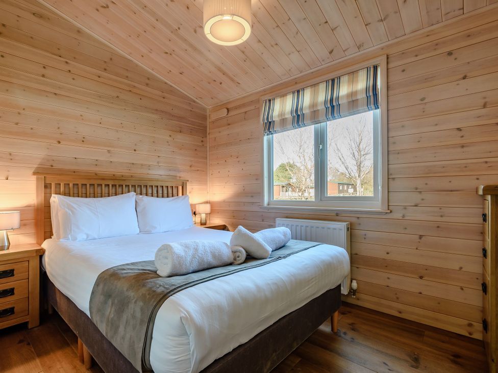 A bedroom with a bed and bedside table at Fir Tree Waterside Spa Carlton Miniott near Thirsk