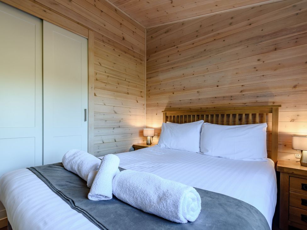 A bedroom with a bed and towels at Fir Tree Waterside Spa Carlton Miniott near Thirsk