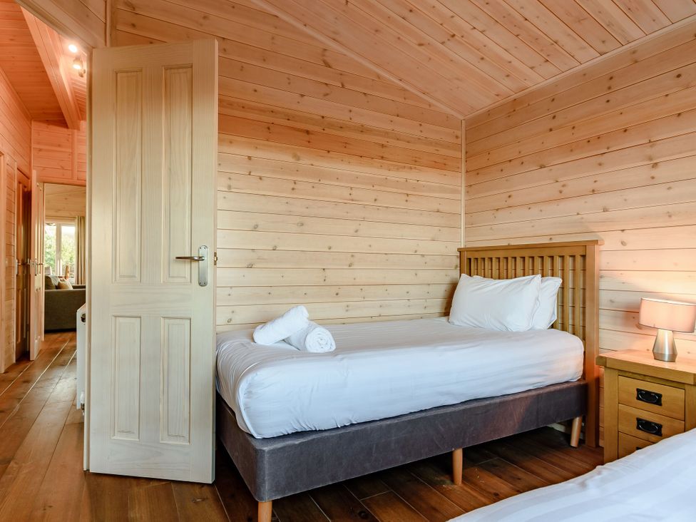 A bedroom with a bed and a bedside table at Fir Tree Waterside Spa Carlton Miniott near Thirsk