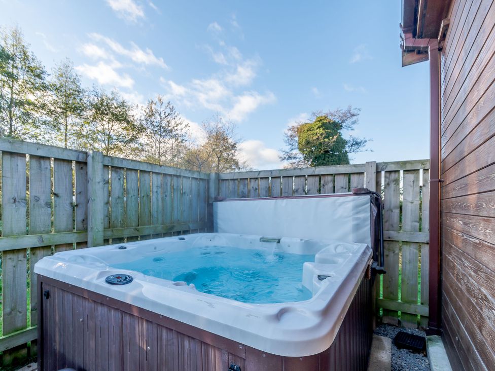 A hot tub surrounded by a wooden fence at Fir Tree Waterside Spa Carlton Miniott near Thirsk