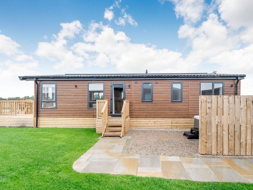 A wooden cabin with steps and a lawn at Spindle Spa Carlton Miniott near Thirsk