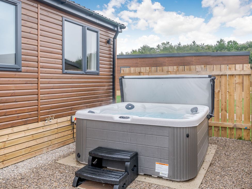 An outdoor area with a hot tub and wooden fence at Spindle Spa Carlton Miniott near Thirsk