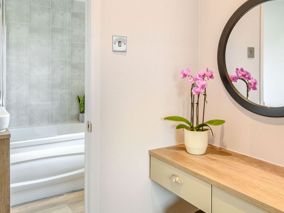 A bathroom with a mirror and plant at Spindle Spa (Pet) Carlton Miniott near Thirsk