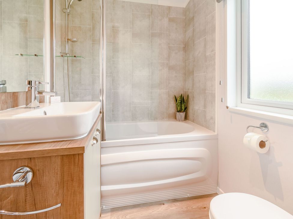 A bathroom with a bathtub, shower, sink, and toilet at Spindle Spa (Pet) Carlton Miniott near Thirsk