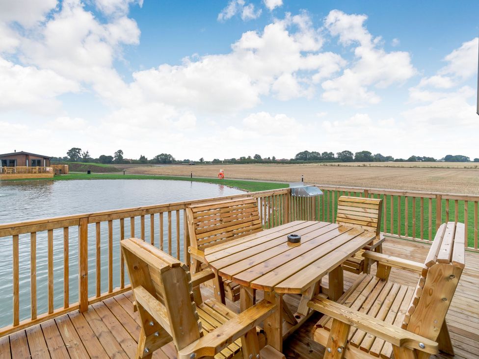 An outdoor seating area with wooden table and chairs at Spindle Spa (Pet) Carlton Miniott near Thirsk