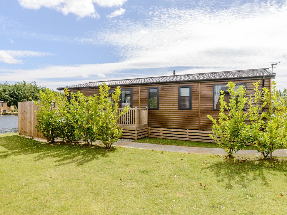 A wooden lodge with steps and bushes at Oak Spa (Pet) Carlton Miniott near Thirsk