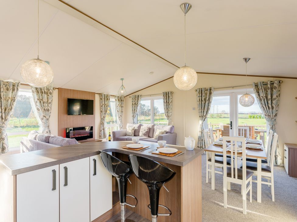 A living room with a sofa, television, and dining area at Oak Waterside Spa (Pet) Carlton Miniott near Thirsk