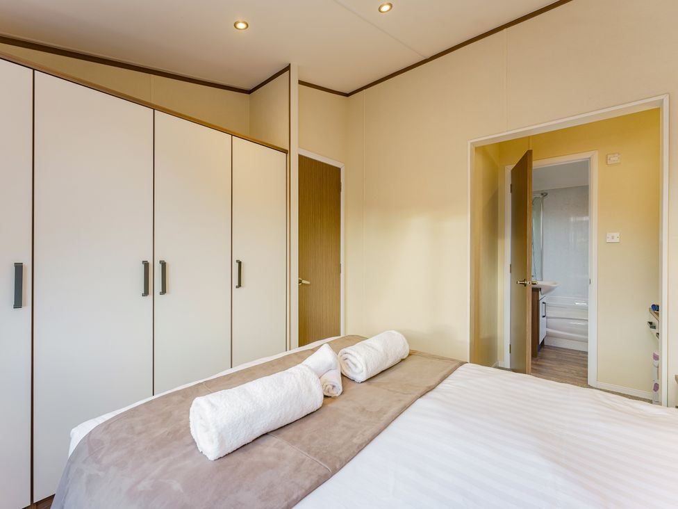 A bedroom with a bed and wardrobe at Oak Waterside Spa (Pet) Carlton Miniott near Thirsk