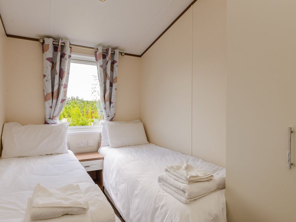 A bedroom with twin beds and a window at Oak Waterside Spa (Pet) Carlton Miniott near Thirsk