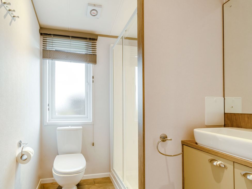 A bathroom with a toilet, sink, and shower at Oak Waterside Spa (Pet) Carlton Miniott near Thirsk