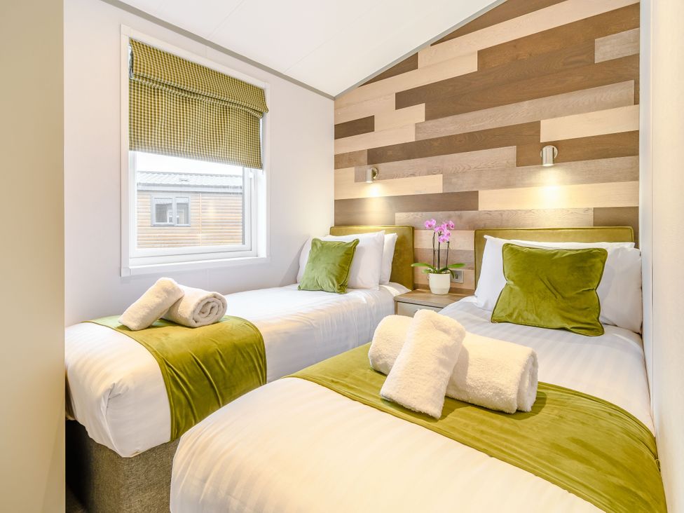 A bedroom with two beds and a window at Oak Waterside Spa (Pet) Carlton Miniott near Thirsk