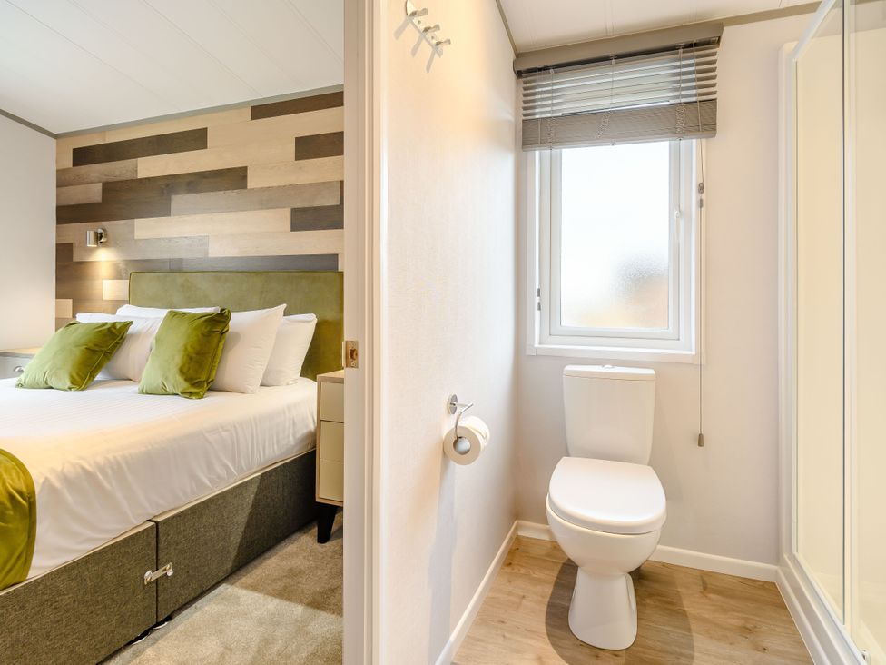 A bedroom with a bed and a toilet area at Oak Waterside Spa (Pet) Carlton Miniott near Thirsk