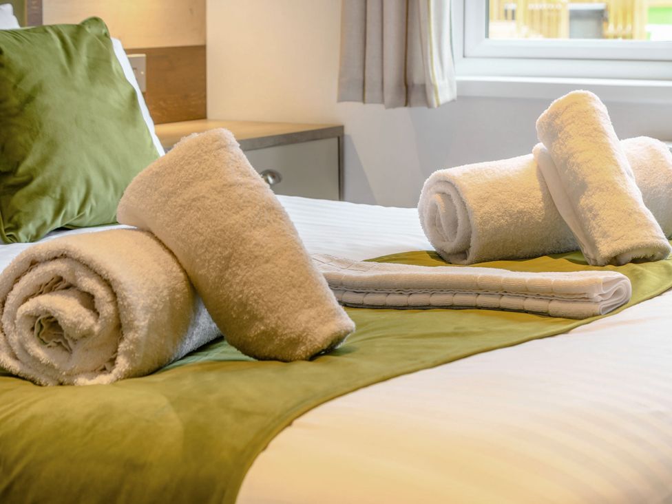 A bedroom with folded towels on the bed at Oak Waterside Spa (Pet) Carlton Miniott near Thirsk