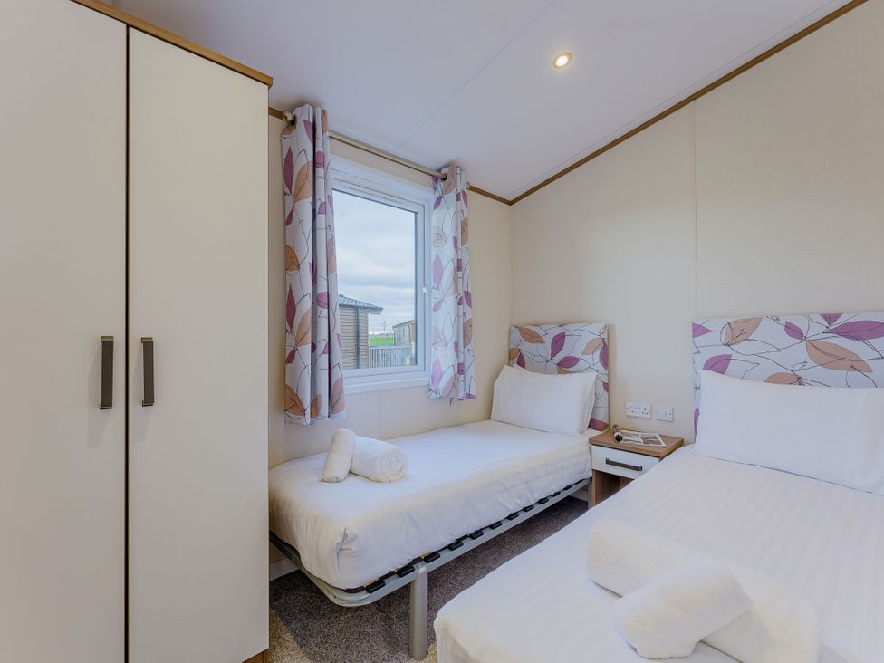 A bedroom with two beds and a window at Larch Waterside Spa Carlton Miniott near Thirsk