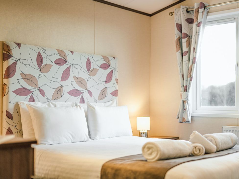 A bedroom with a bed, pillows, and lamp at Larch Waterside Spa in Carlton Miniott near Thirsk