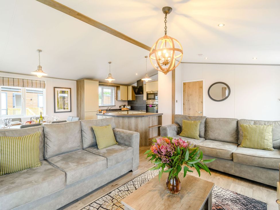 A living room with sofas, coffee table, and kitchen area at Beech Waterside Spa, Carlton Miniott near Thirsk