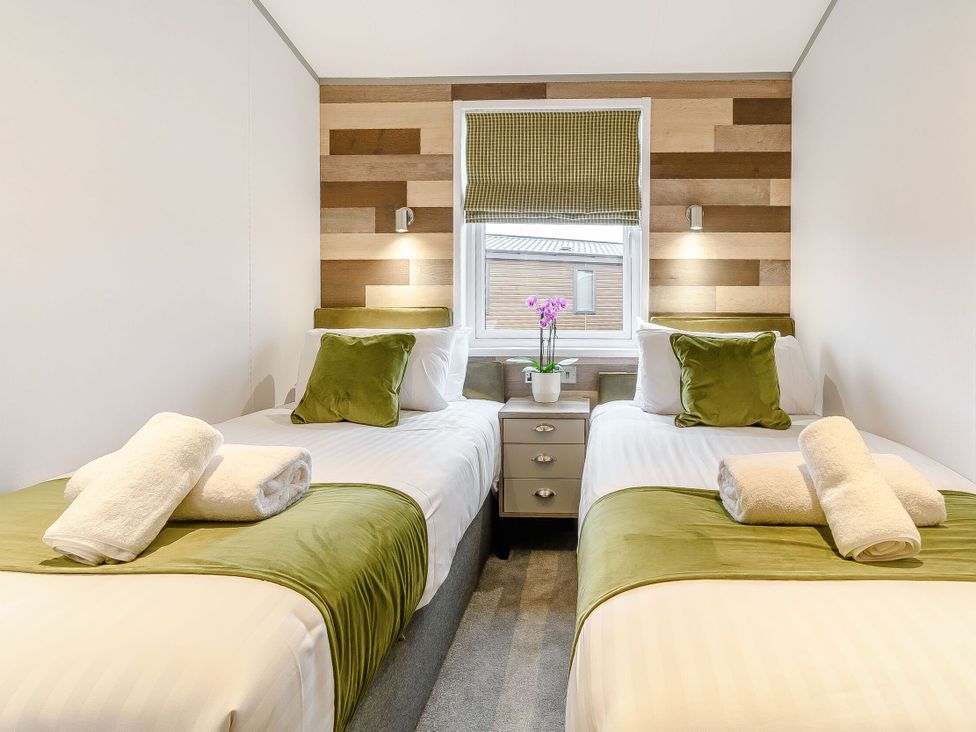 A bedroom with two beds and a nightstand at Beech Waterside Spa (Pet) Carlton Miniott near Thirsk