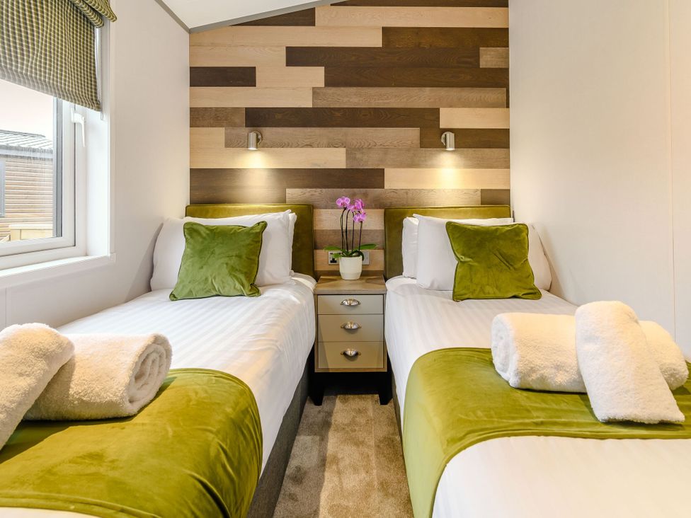 A bedroom with two beds and a nightstand at Beech Waterside Spa (Pet) Carlton Miniott near Thirsk