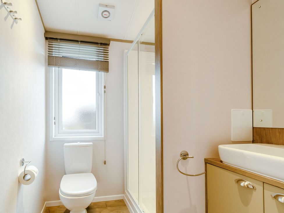 A bathroom with a toilet, shower, sink, and window at Beech Waterside Spa (Pet) Carlton Miniott near Thirsk