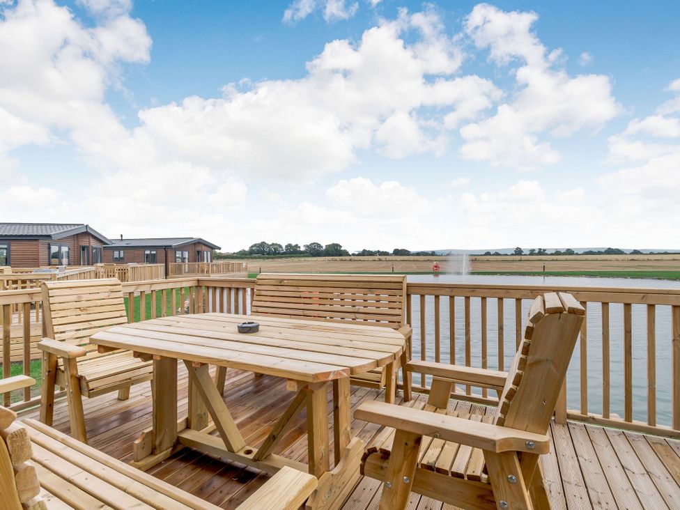 An outdoor area with wooden deck furniture at Beech Waterside Spa (Pet) Carlton Miniott near Thirsk