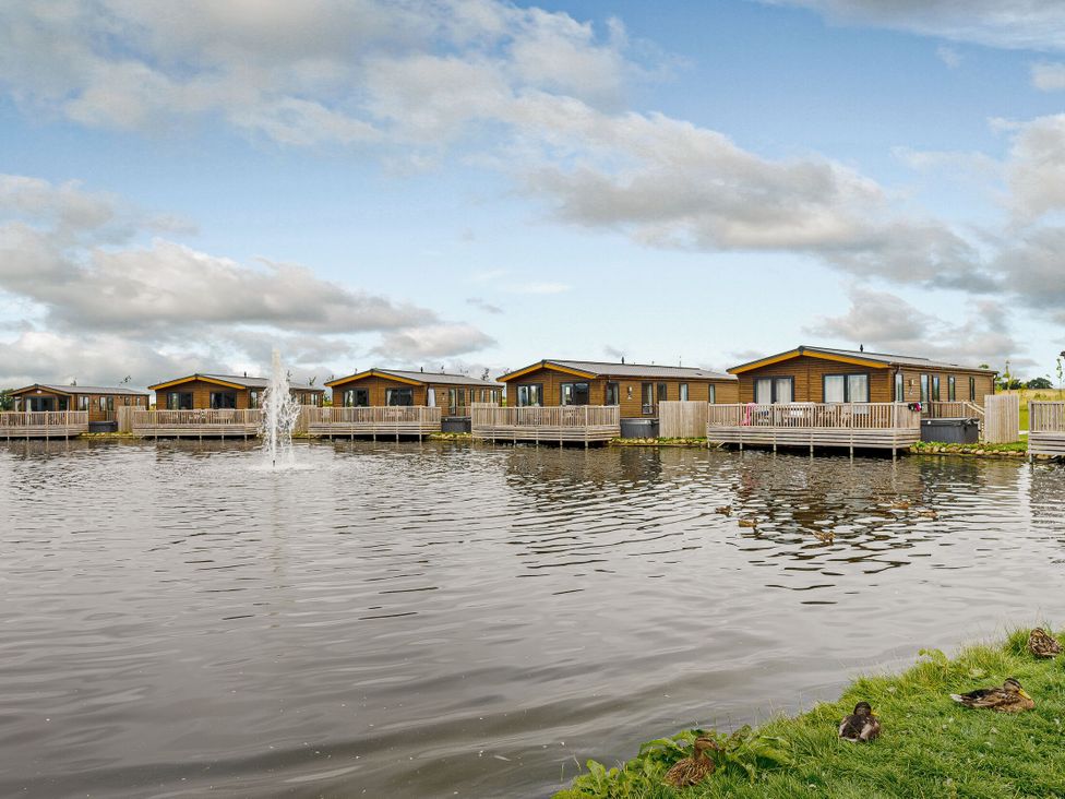 Cabins beside a pond with a fountain at Larch Waterside Spa (Pet) Carlton Miniott near Thirsk