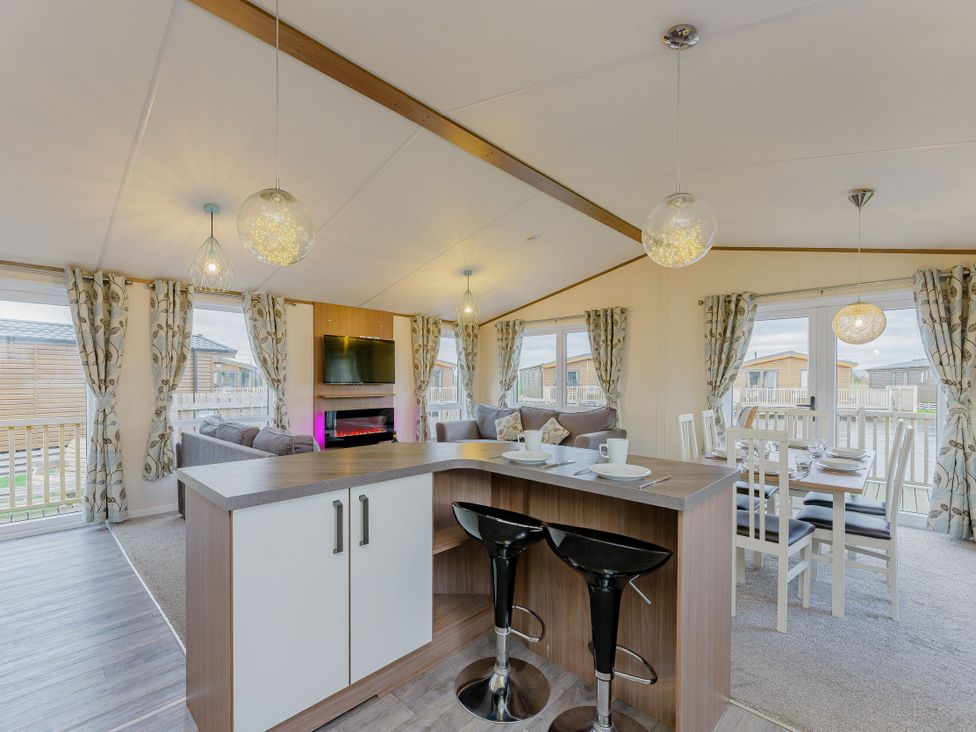 A living room with a kitchen island and dining area at Larch Waterside Spa (Pet) Carlton Miniott near Thirsk