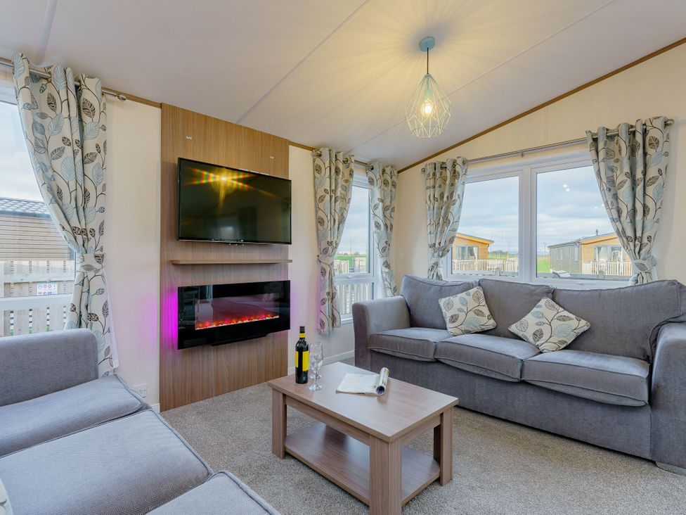 A living room with a sofa and television at Larch Waterside Spa (Pet) Carlton Miniott near Thirsk