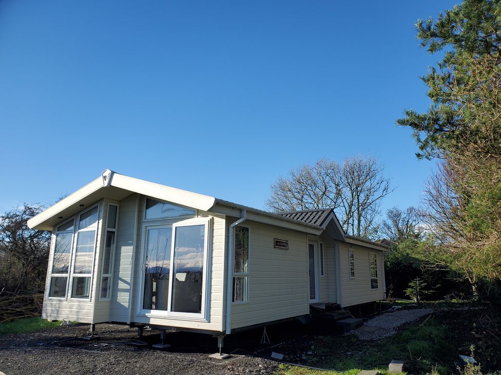 A house with large windows and a pathway at Plas Marchog Lodge in Pentraeth