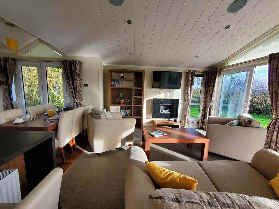 A living room with a sofa and dining table at Plas Marchog Lodge in Pentraeth