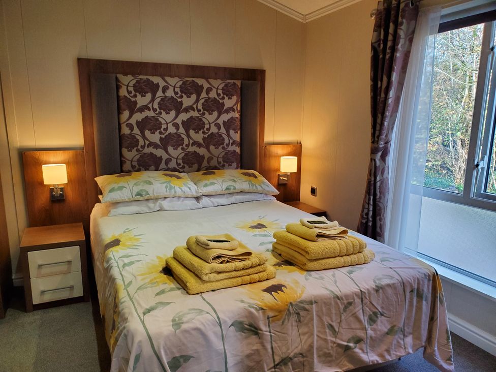 A bedroom with a bed and towels at Plas Marchog Lodge, Pentraeth