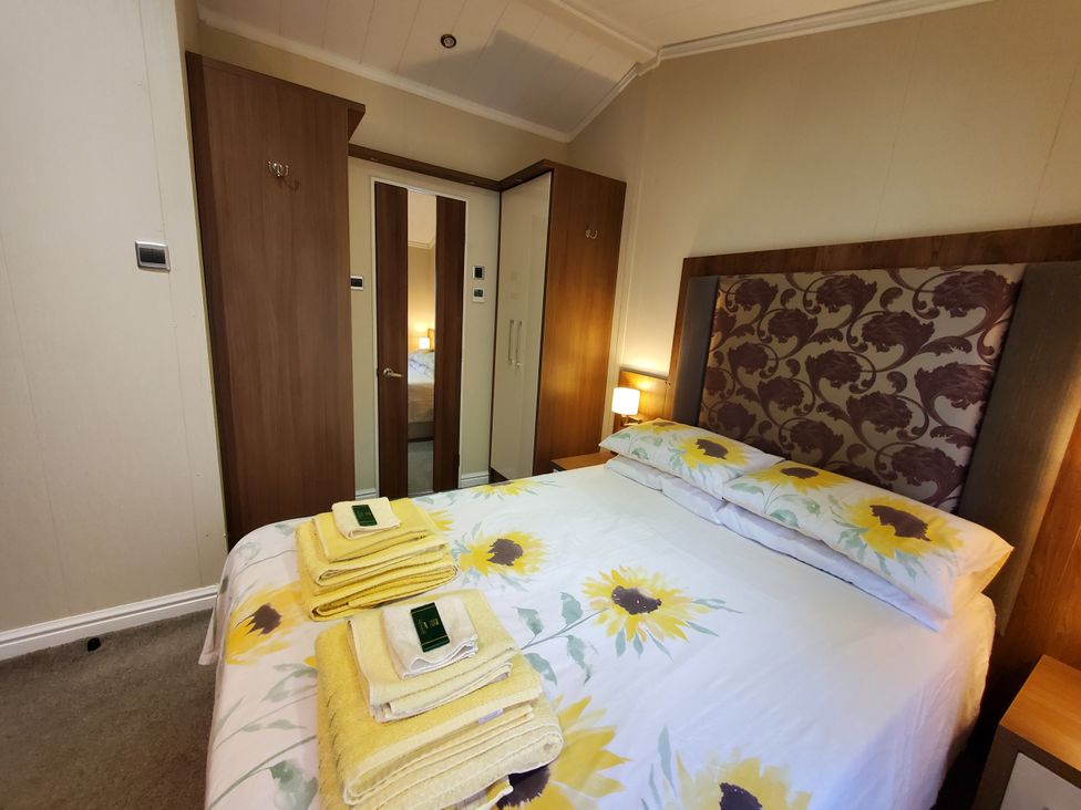 A bedroom with a bed and towels at Plas Marchog Lodge in Pentraeth