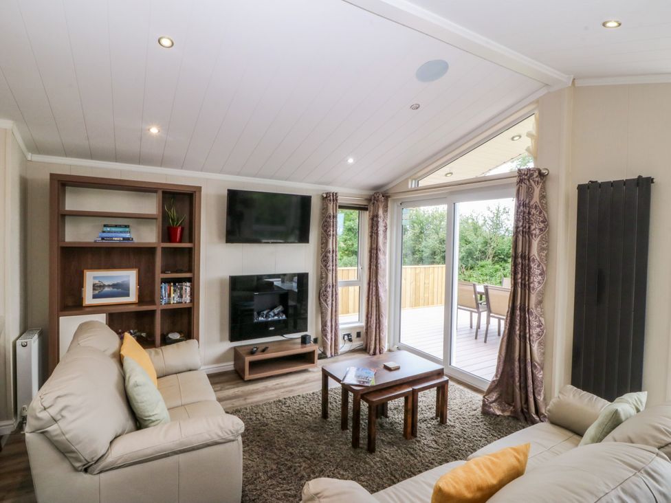 A living room with a sofa and television at Plas Marchog Lodge Rhoscefnhir near Pentraeth