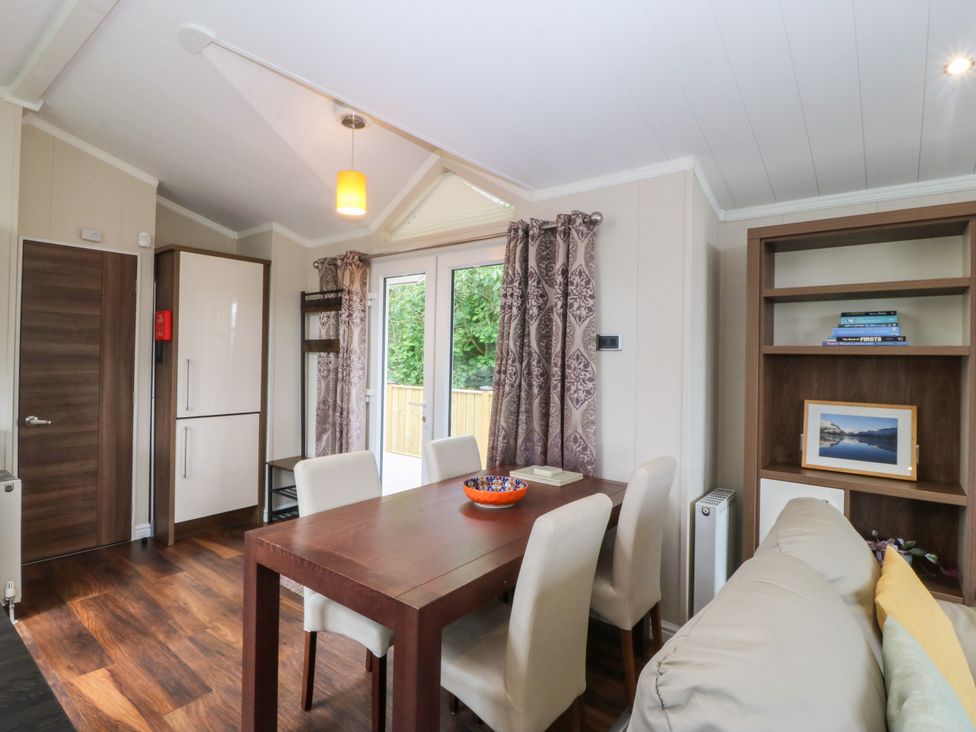 A dining room with a table and chairs at Plas Marchog Lodge near Rhoscefnhir