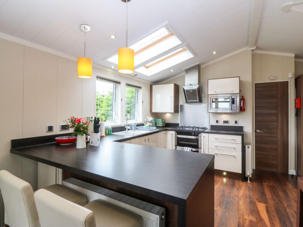 A kitchen with appliances and a kitchen island at Plas Marchog Lodge Rhoscefnhir near Pentraeth