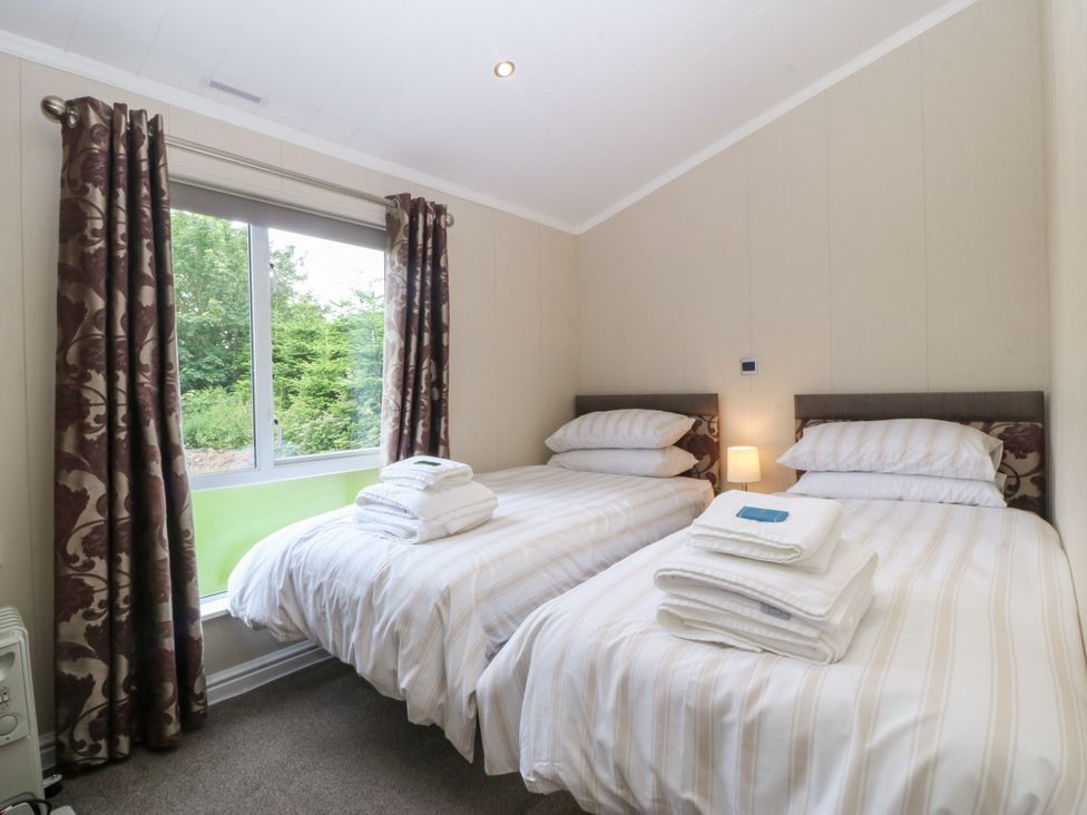 A bedroom with two beds and a window at Plas Marchog Lodge Rhoscefnhir near Pentraeth