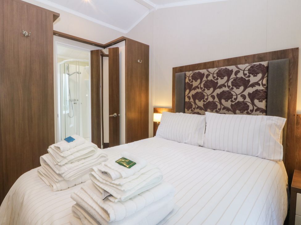 A bedroom with a bed and towels at Plas Marchog Lodge in Rhoscefnhir near Pentraeth