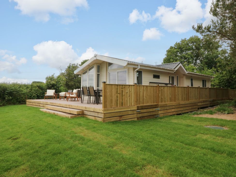 An outdoor area with a deck and seating at Plas Marchog Lodge Rhoscefnhir near Pentraeth