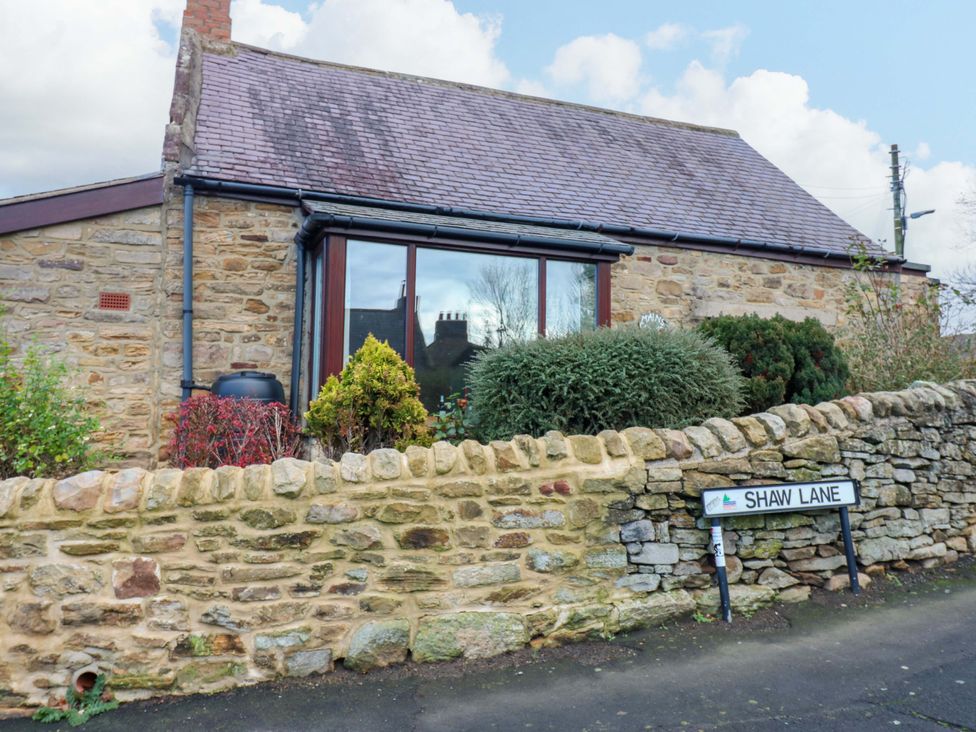 A house with a stone wall and a street sign at Mains Cottage in Consett