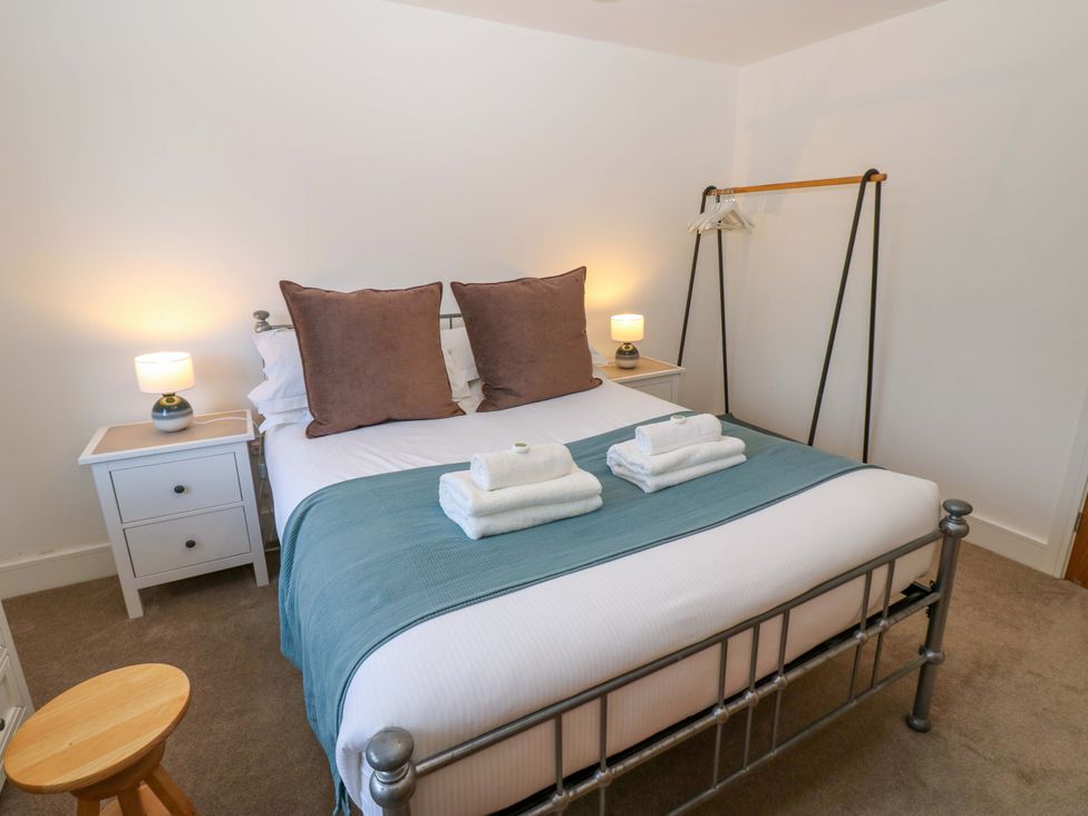 A bedroom with a bed, bedside table, and clothes rack at Mains Cottage in Consett