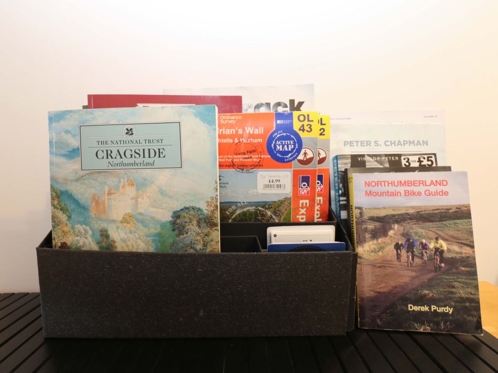 A collection of books and maps in a box in the living room at Mains Cottage Consett