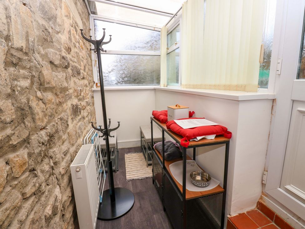 A conservatory with coat rack and shelves at Mains Cottage in Consett