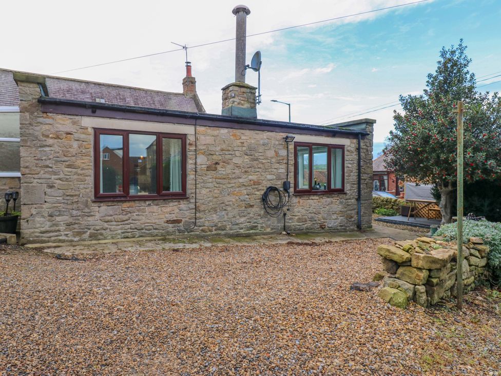 An outdoor area with a stone wall and gravel at Mains Cottage in Consett